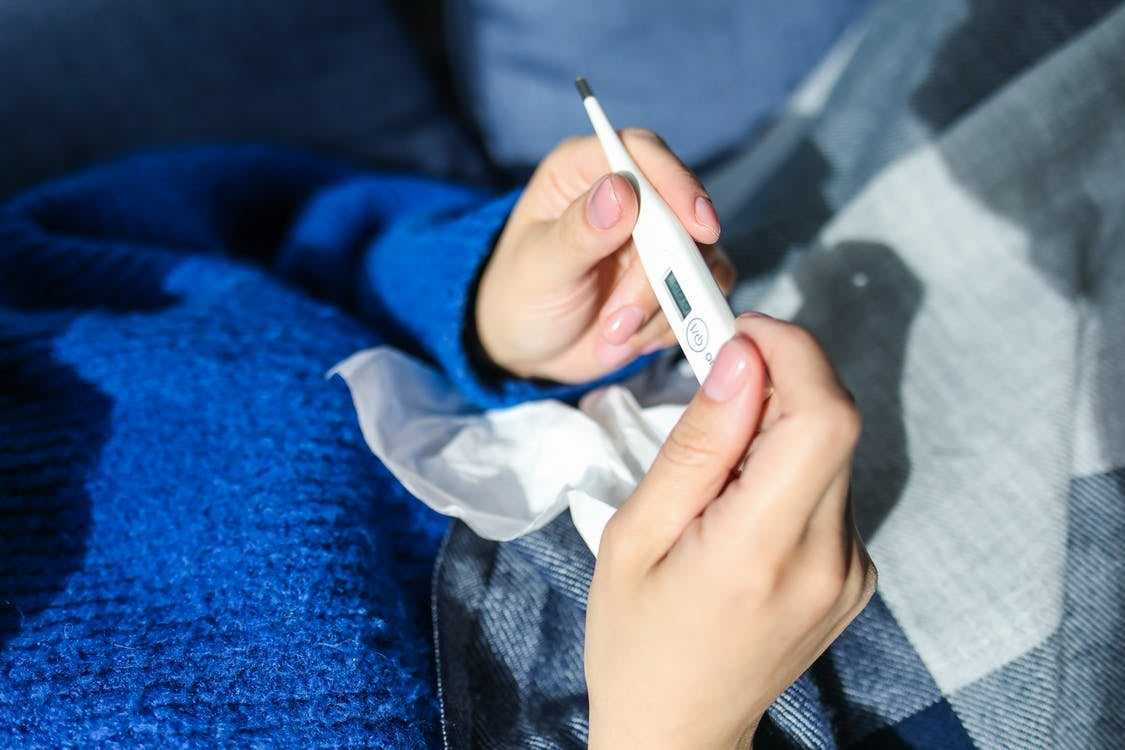 A person checking their temperature with a  thermometer